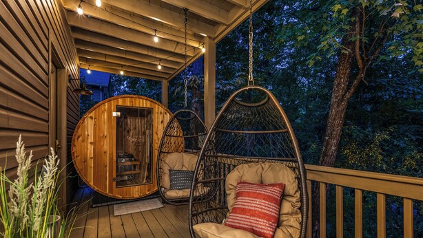 A wooden deck with two hanging chairs and a wooden cabin structure.