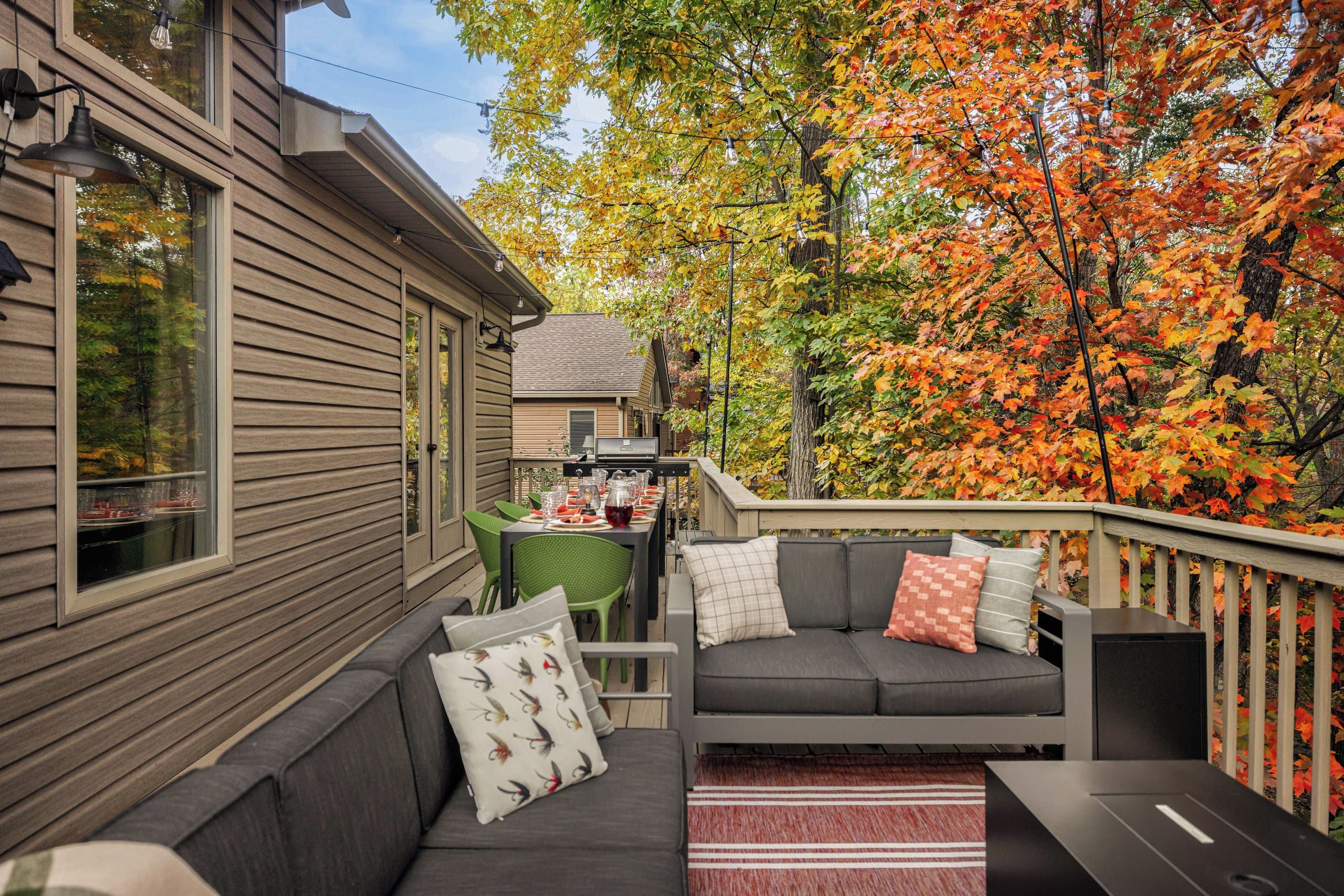 A covered outdoor seating area with a sofa and chairs, a dining table with chairs, and a grill.