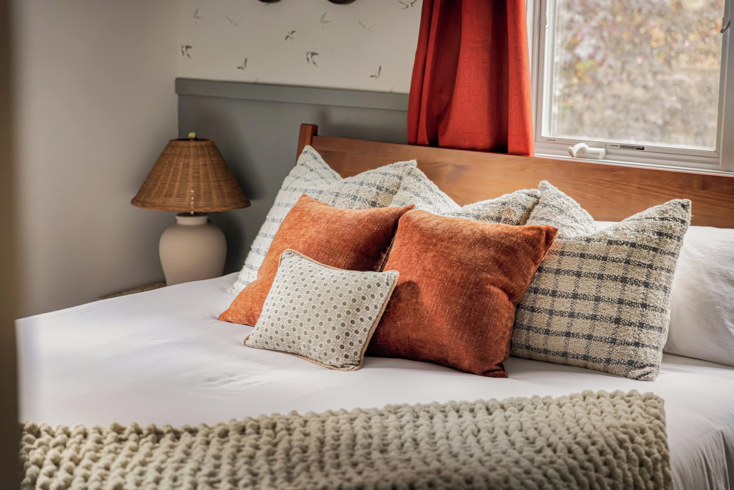 A bed with multiple pillows and a knitted throw blanket.