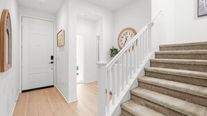 A staircase with a wooden handrail and carpeted steps leading to a landing.