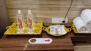 A hotel reception area with a wooden counter, a tray with bottled water, a card holder, and rolled towels. - Hotel Naman Palace (Varanasi)