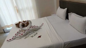 A neatly made bed with a welcome message and a swan decoration. - Hotel Naman Palace (Varanasi)