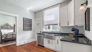 A modern kitchen with white cabinets, a stainless steel sink, and a window with blinds. - Old City Charm l Historic l Walk to St George (St. Augustine)