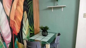 A dining area with a glass table and chairs, a potted plant, and a wall with a leaf-patterned design. - OYO 1170 Mvm Transient Home Pasay (Pasay)