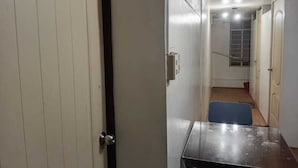 A narrow hallway with a door marked '1' on the left, a small table in the center, and a staircase leading to another room. - OYO 1170 Mvm Transient Home Pasay (Pasay)