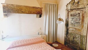 A bedroom with a bed, a bedside table, a lamp, and a wardrobe.