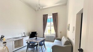 Una sala de estar moderna con comedor, un sofá, una araña y vistas al exterior.