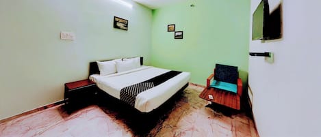 A bedroom with a bed, a chair, a ceiling fan, and a wall-mounted TV.