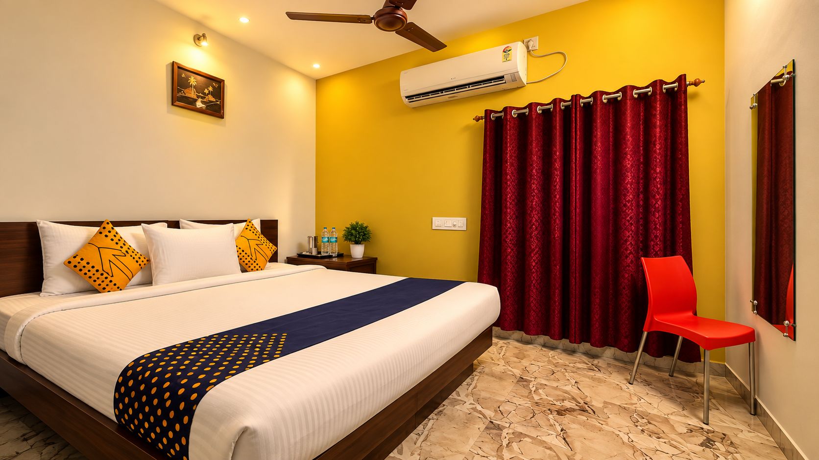 Habitación de hotel con cama, una silla roja, unidad de aire acondicionado y ventilador de techo.