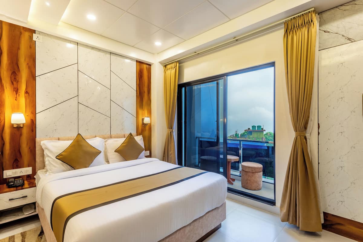 Habitación de hotel moderna con una cama grande, una pared decorativa de madera, una puerta de cristal que da a un balcón y vistas a la ciudad.
