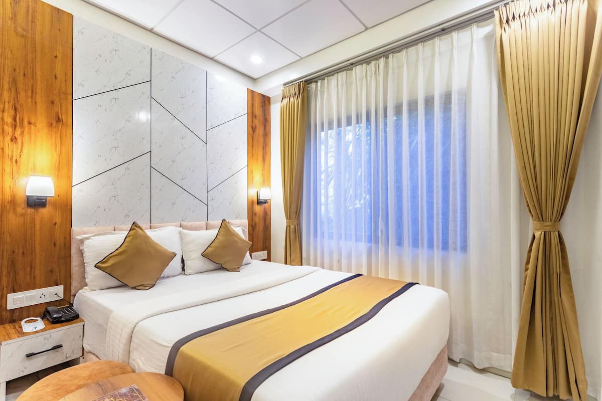 Habitación de hotel moderna con una cama grande, paneles de madera, diseño geométrico en la pared y vistas a través de cortinas translúcidas.