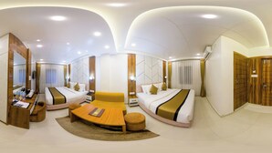 A modern hotel room with a curved ceiling, a sofa bed, a wooden desk, and a small table.