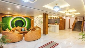A modern lobby with a reception desk, seating area, and a staircase.