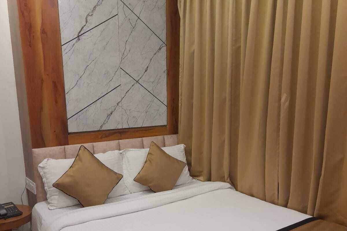 Una cama bien tendida con una paleta de colores blanco y marrón, un cabecero de madera y un cuadro abstracto grande encima.