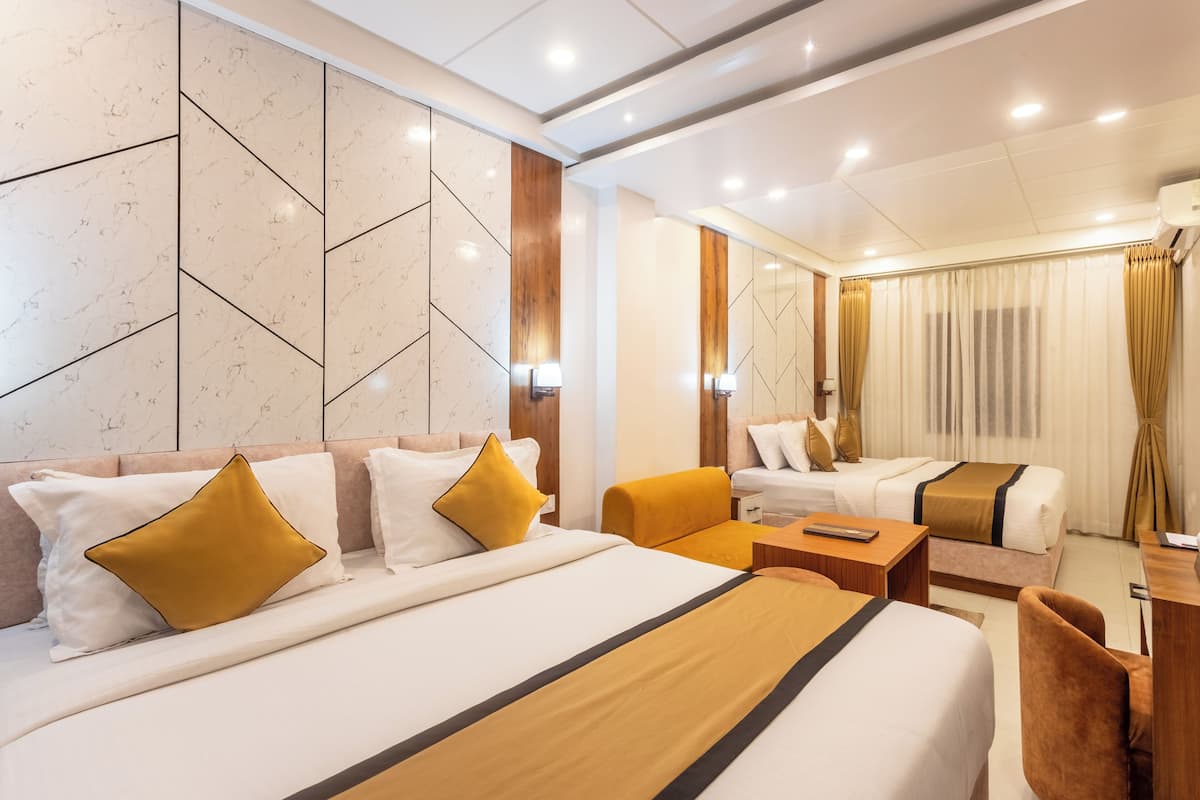 Una habitación de hotel con una cama grande, una cama más pequeña, un escritorio y una silla.