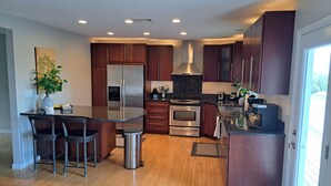 Una cocina moderna con una isla central, electrodomésticos de acero inoxidable y armarios de madera.