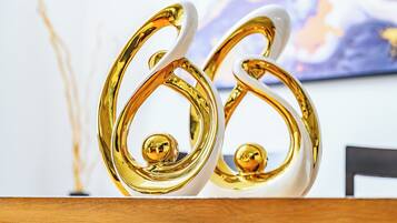 Two golden, white, abstract sculptures on a wooden surface.