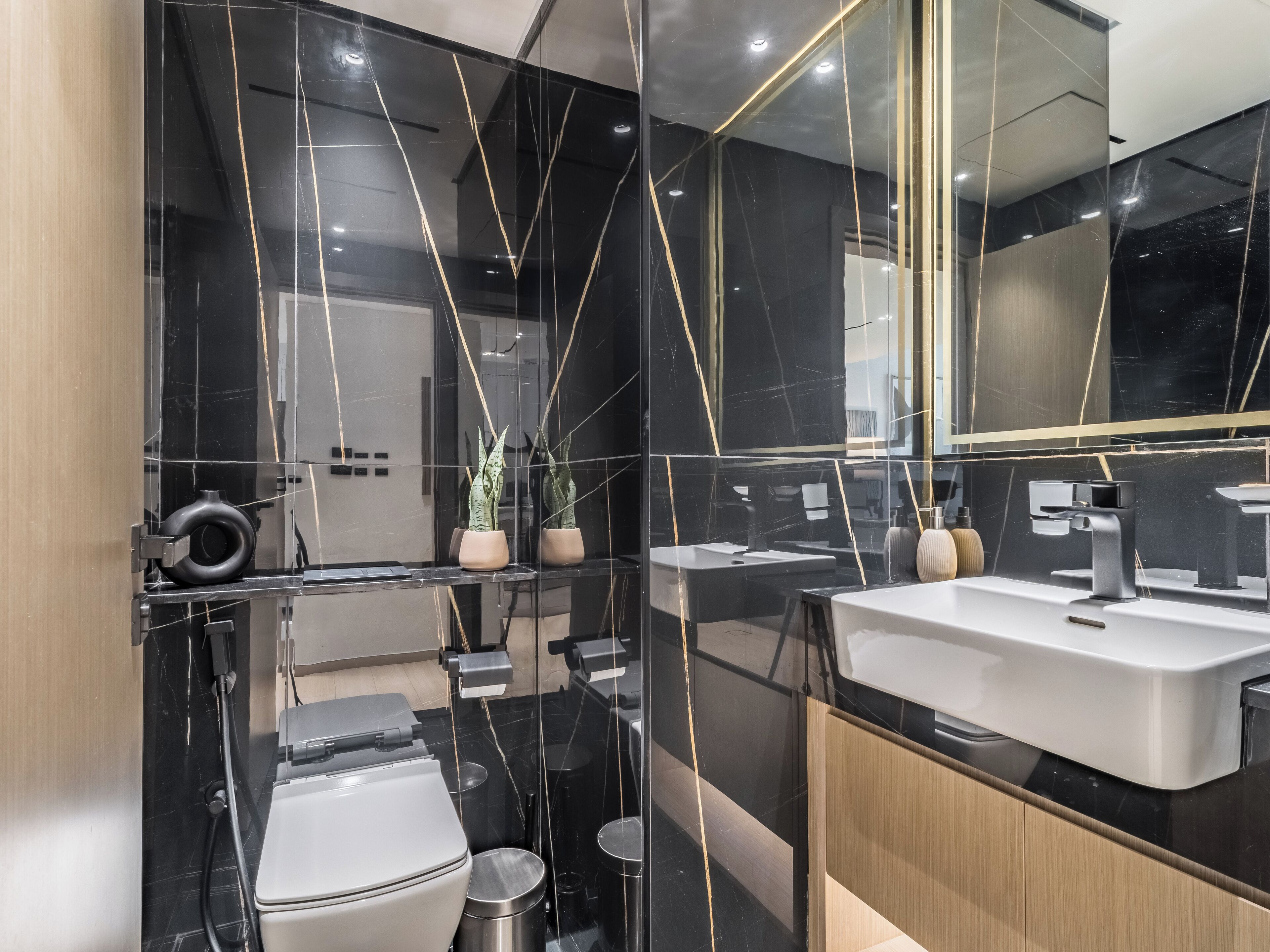 Une salle de bain moderne avec un meuble-lavabo en marbre noir, un lavabo blanc et des toilettes.