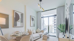 Ein modernes Wohnzimmer mit Essbereich, einer Couch, einem Hängesessel und einem großen Fenster mit Blick auf die Stadt.