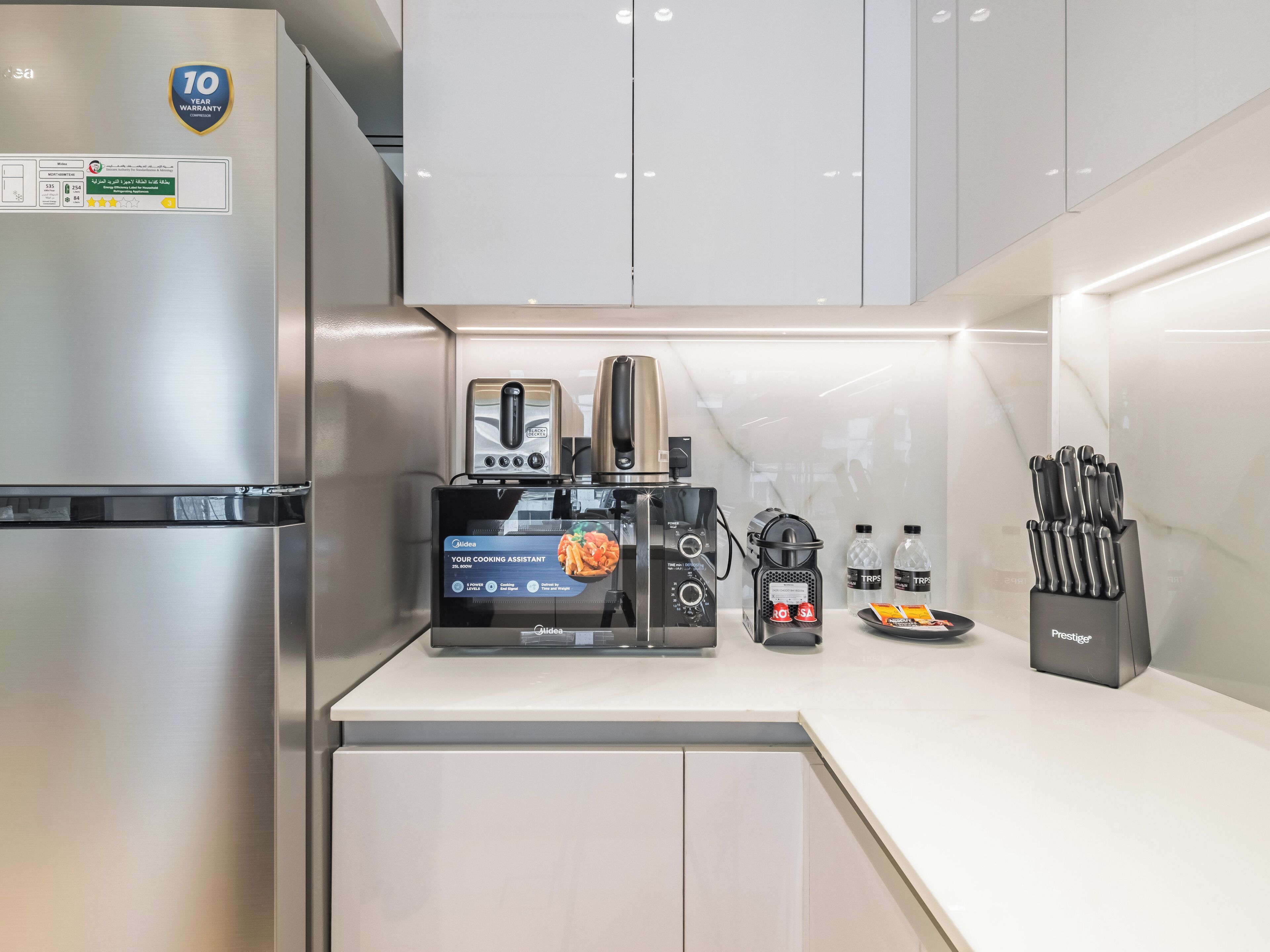 A modern kitchen with a stainless steel refrigerator, a coffee machine, a toaster, and a knife block.