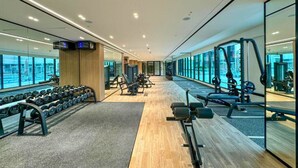 Ein modernes Fitnessstudio mit Spiegelwänden, verschiedenen Trainingsgeräten und Holzboden.