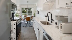 A modern kitchen with white cabinets, a stainless steel refrigerator, a built-in oven, a coffee maker, and a toaster. - Artsy Capitol Hill Gem City View Workspace Parking (Seattle)