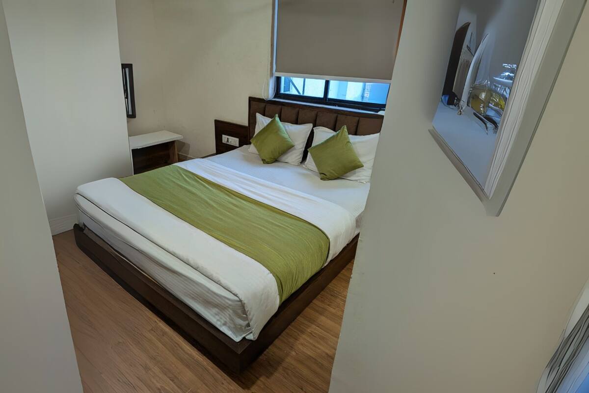 Un dormitorio ordenado con cama, mesita de noche y espejo.