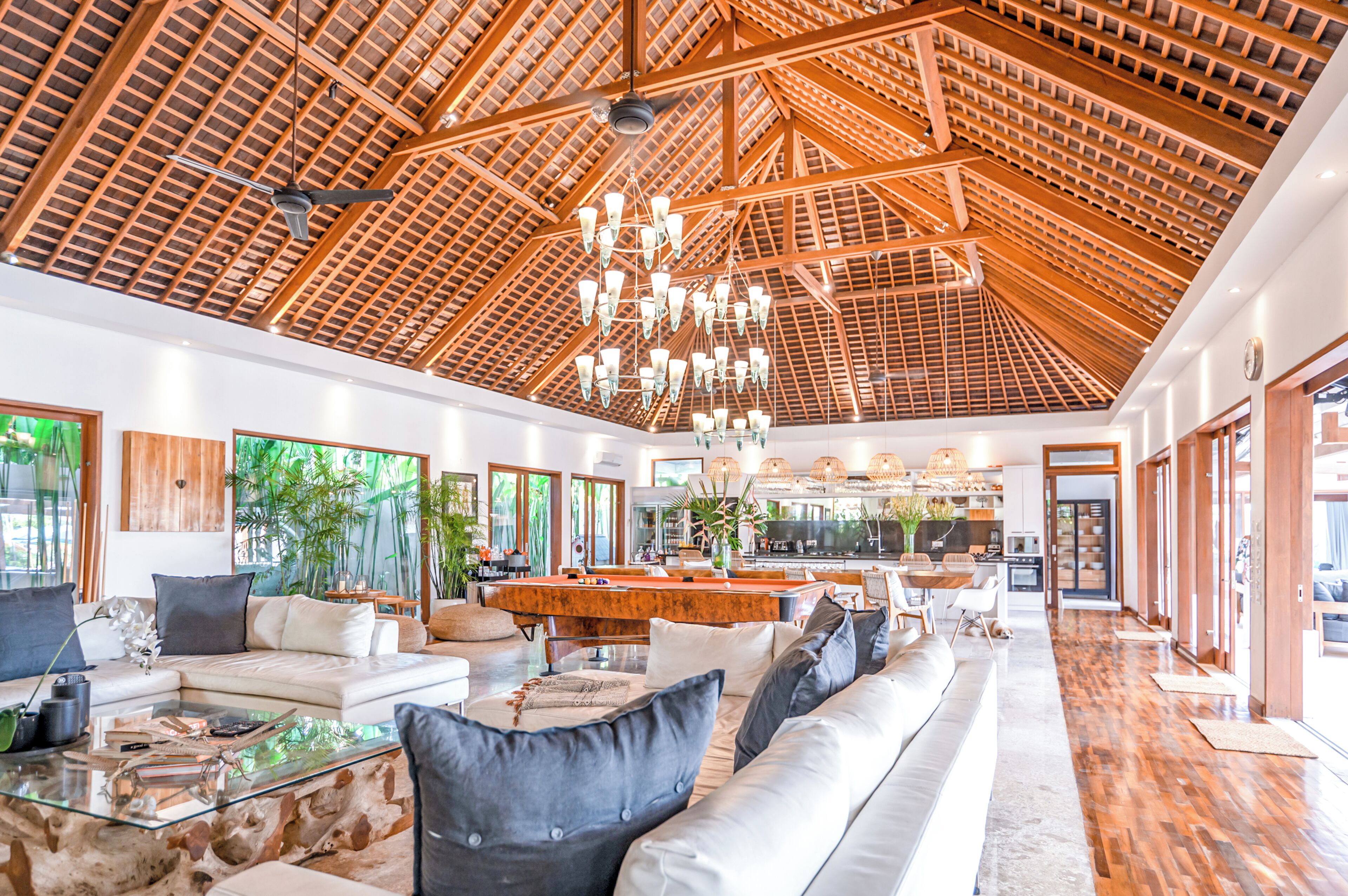 A spacious living area with a high ceiling, wooden beams, and a central island with seating.