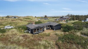A modern house with a large deck, surrounded by natural dunes and vegetation. - Well-kept 70s holiday home near the North Sea (Hvide Sande)