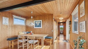 A wooden interior with a dining table, benches, pendant lights, framed artwork, and a wooden floor. - Well-kept 70s holiday home near the North Sea (Hvide Sande)