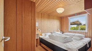 A wooden-paneled room with a bed, bedside lamps, and a window with a view. - Well-kept 70s holiday home near the North Sea (Hvide Sande)