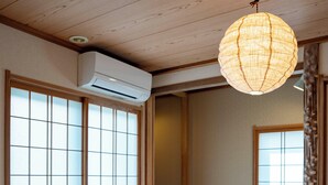 Une pièce de style japonais traditionnel, avec un sol recouvert de tatamis, un futon servant de lit, des portes coulissantes en papier de riz (shoji) et une lanterne en papier suspendue.