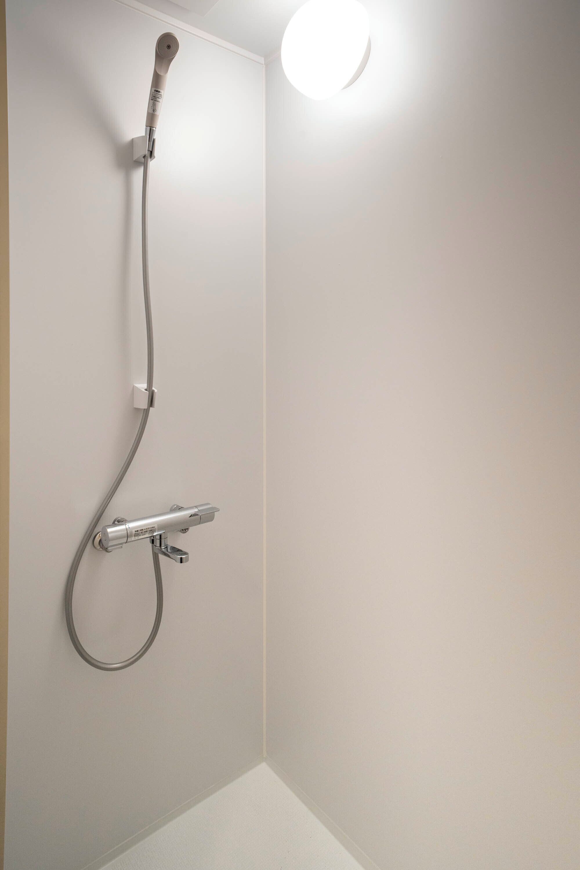 Een moderne douche met douchefus en handdouche.