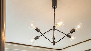 Une pièce moderne dotée d’une grande fenêtre, d’un plancher en bois, d’un canapé blanc, d’une table en bois et d’un luminaire au plafond.