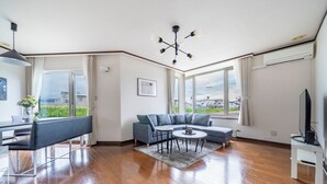 Un salon moderne avec un canapé d’angle, une table à manger et un téléviseur.