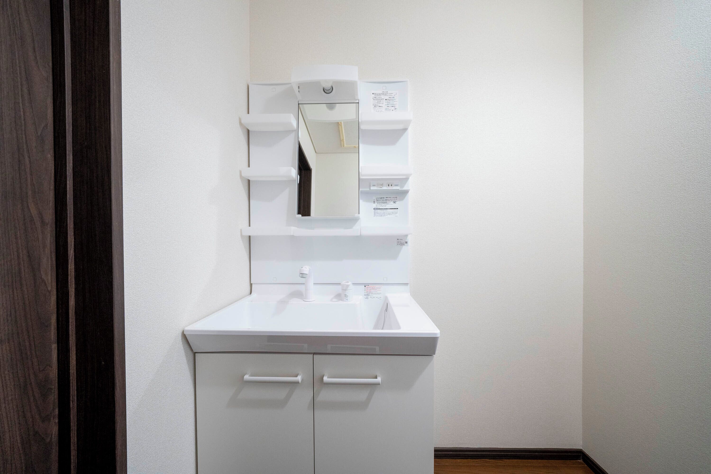 A white bathroom with a sink, mirror, and storage cabinets.