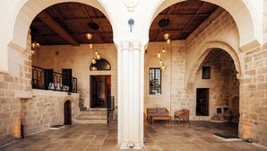 A spacious interior with stone walls, wooden beams, and arched doorways.