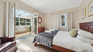 A bedroom with a large bed, a wooden headboard, a nightstand, a red chair, and a sliding glass door leading to a balcony. - Katoomba Getaway 1 -Perfectly positioned in a quiet, street just a hop, skip & jump to Katoomba town (Katoomba)