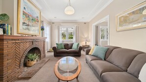 A living room with a fireplace, two sofas, a coffee table, and artwork on the walls. - Katoomba Getaway 1 -Perfectly positioned in a quiet, street just a hop, skip & jump to Katoomba town (Katoomba)