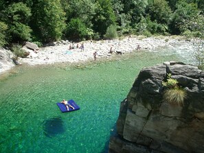 Ein klarer Fluss, in dem Menschen schwimmen, und eine Felsformation mit Blick auf den Fluss.