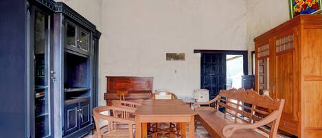 A spacious room with a wooden dining table, chairs, a sofa, and a cabinet.