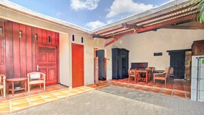 Une cour avec un sol carrelé, des meubles en bois et une porte rouge.