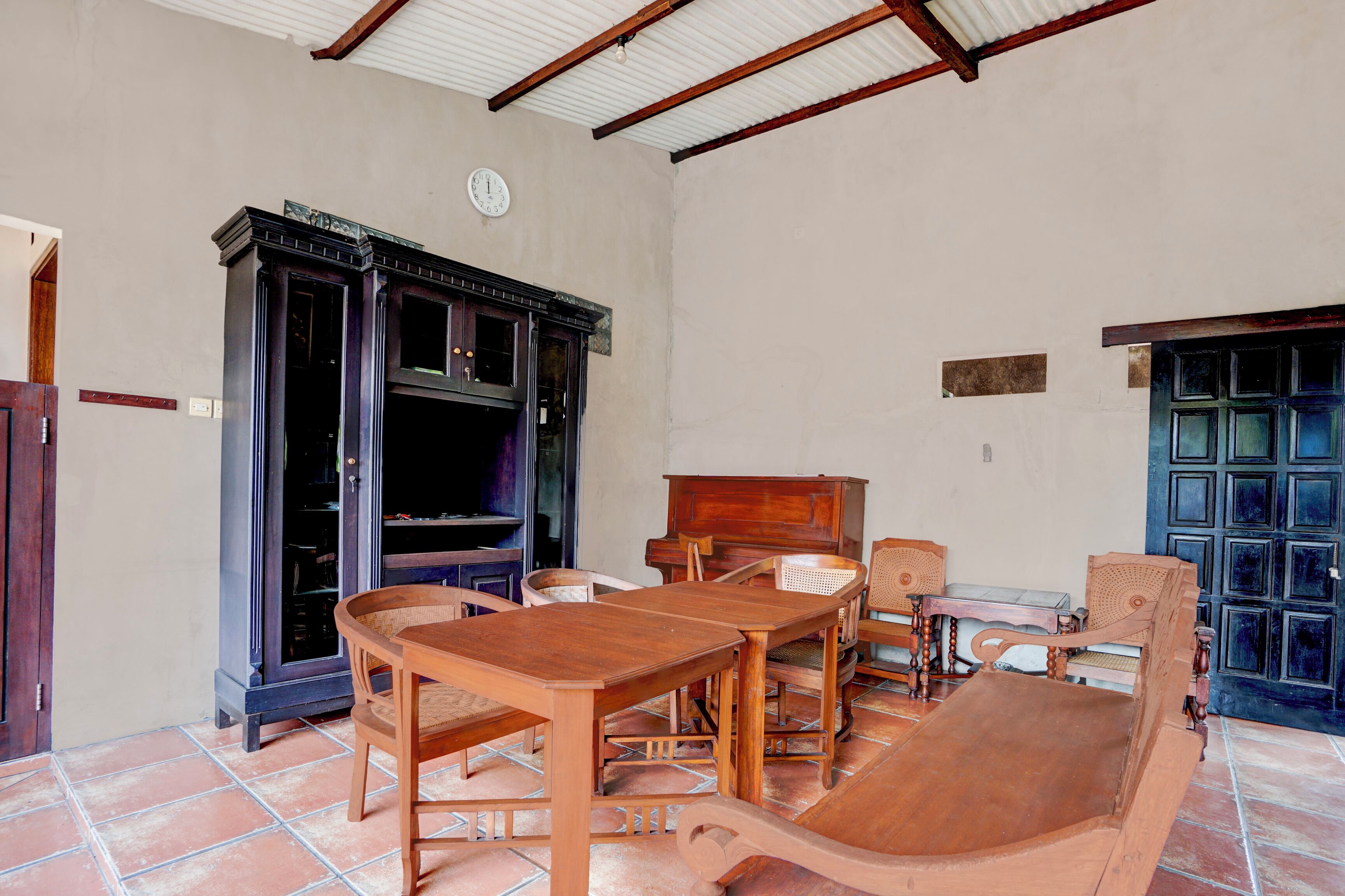 A room with a wooden dining table, chairs, a cabinet, and a door with a grid pattern.
