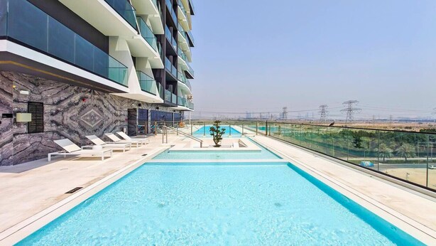 A swimming pool with lounge chairs and a view of the surrounding area. - Binghatti Heights Residences- JVC (Dubai)