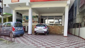 A covered parking area with a checkered floor, two cars parked, and a 'Holiday Home' sign above. - The Executive Inn (Guwahati)