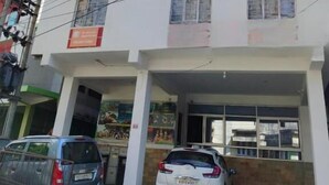 A multi-story building with a parking area in front. - The Executive Inn (Guwahati)