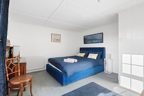 A bedroom with a bed, a chair, a desk, and a painting on the wall. - Spacious 6-Bed Home Surrounded by Nature (Lincolnshire)