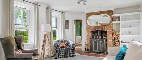 Una sala de estar con chimenea, un sofá, un sillón y una lámpara.