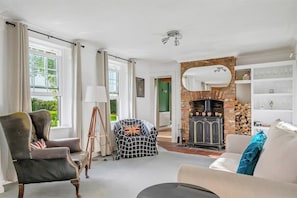 A living room with a fireplace, a sofa, a chair, and a lamp. - Spacious 6-Bed Home Surrounded by Nature (Lincolnshire)