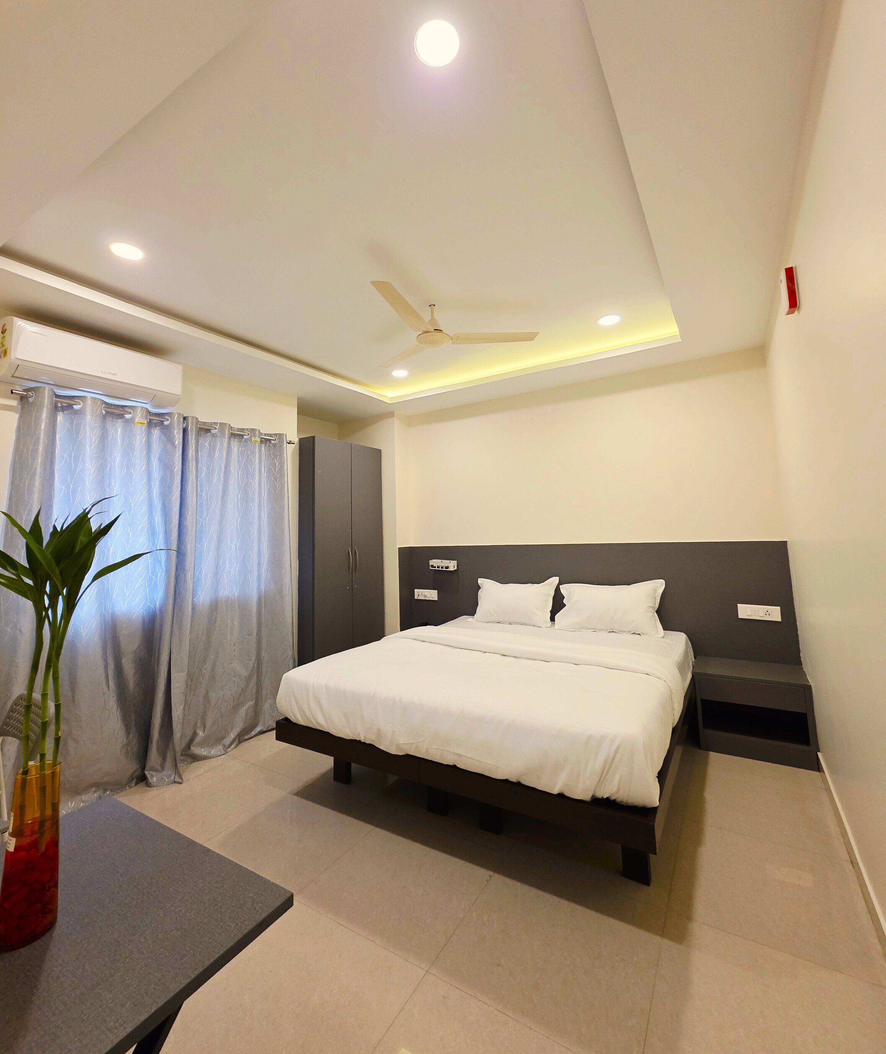 A modern bedroom with a bed, bedside tables, a ceiling fan, and an air conditioning unit.